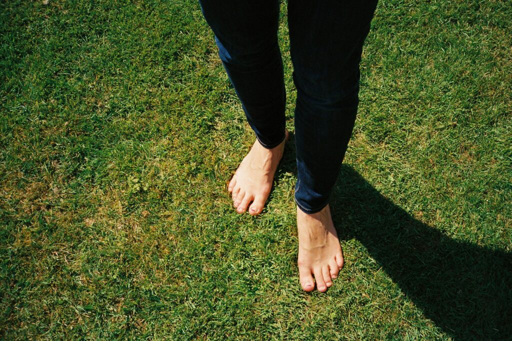 Barefoot grounding on green grass showing earthing therapy practice for daily wellness