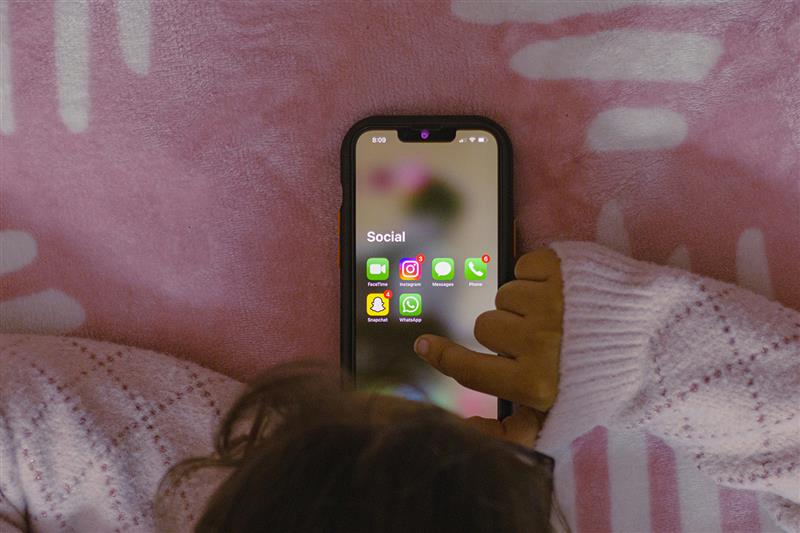 Teen using social media apps in bedroom - Instagram, Snapchat, WhatsApp visible on phone screen, demonstrating bedroom phone addiction affecting sleep